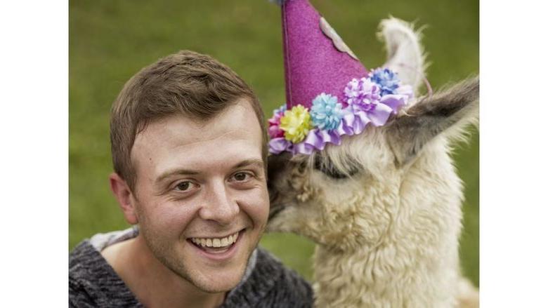 Comedian Derrick Knopsnyder being kissed by a llama